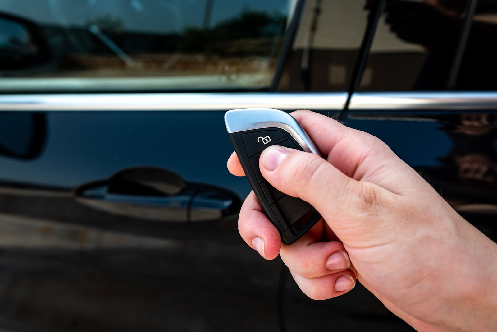 Je vaše auto zabezpečené proti krádeži? | WebJET CMS Ruka držící černý klíč od auta s palcem na tlačítku zamykání.