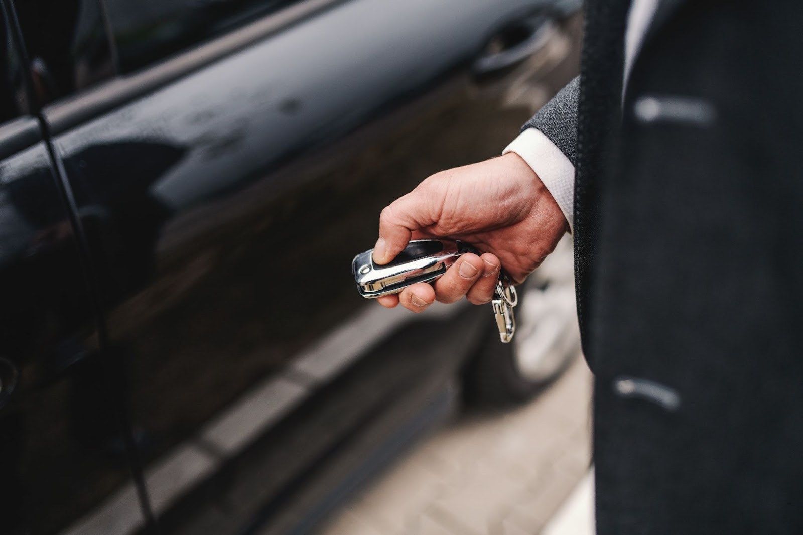 Co všechno potřebujete při přepisu auta? | WebJET CMS Pán v obleku odemyká své černé auto.